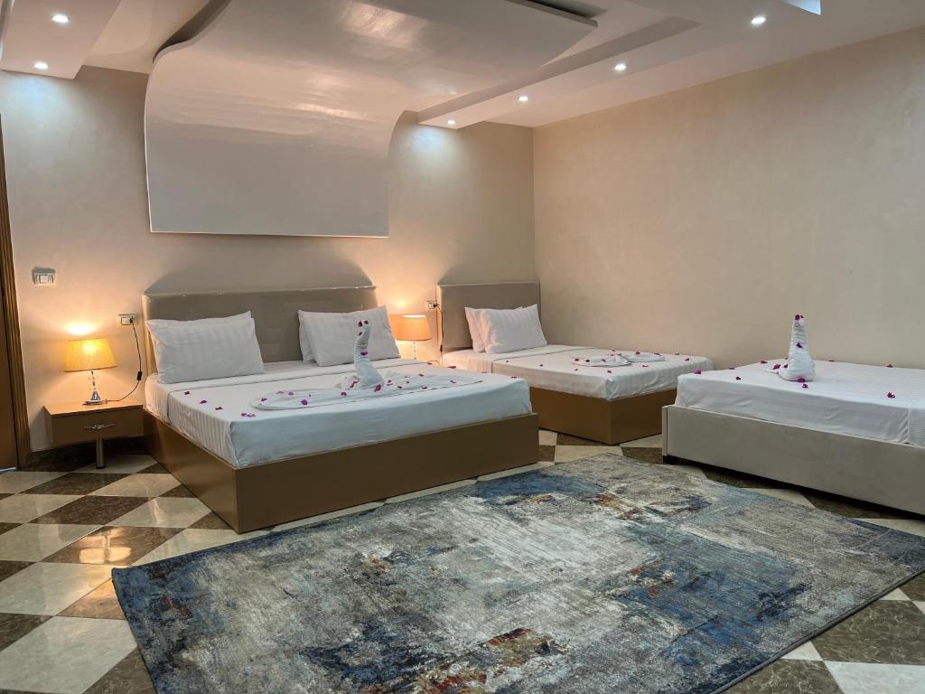 埃兹贝特Pyramids Desert Gate Hotel的配有两张床铺的房间里,配有两盏灯和一张地毯