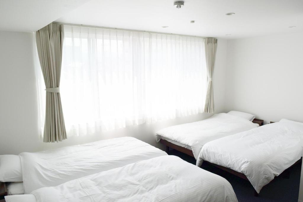 金泽Center Point In Kanazawa的带窗户的客房内的两张床