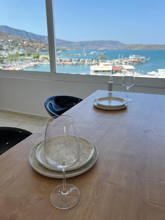 伊罗达Elounda Port Apartment的两张酒杯坐在木桌旁,享有美景