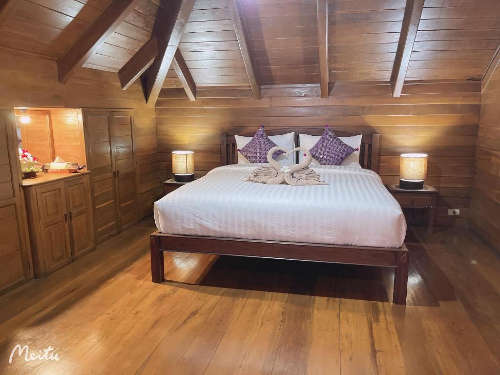 Ban Pa MuangLantana House的一间卧室配有一张大床,桌子上放着两盏灯