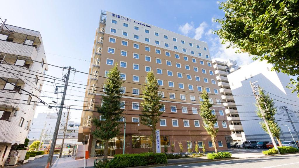 府中市Toyoko Inn Tokyo Keio-sen Higashi-fuchu-eki Kita-guchi的一条街道上一座大建筑,前面有树木