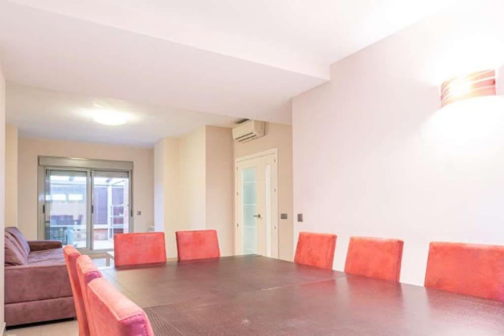 马德里Impresionante apartamento de 4 dormitorios 3 baños y 2 plazas de garaje的一间带长桌和红色椅子的用餐室