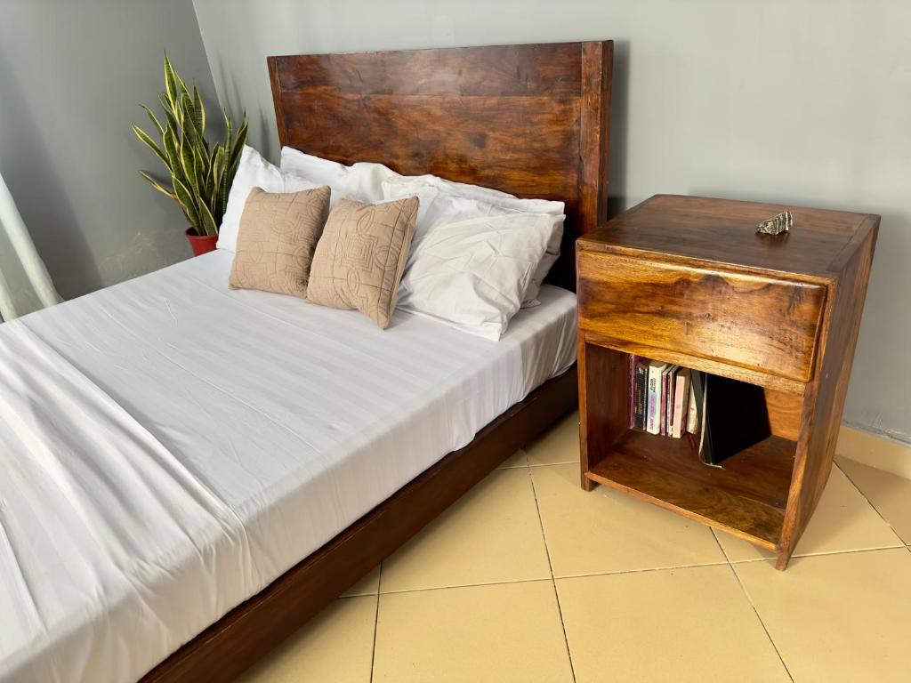 达累斯萨拉姆Sally's home-near JNIA airport的一张带木制床头板和木桌的床