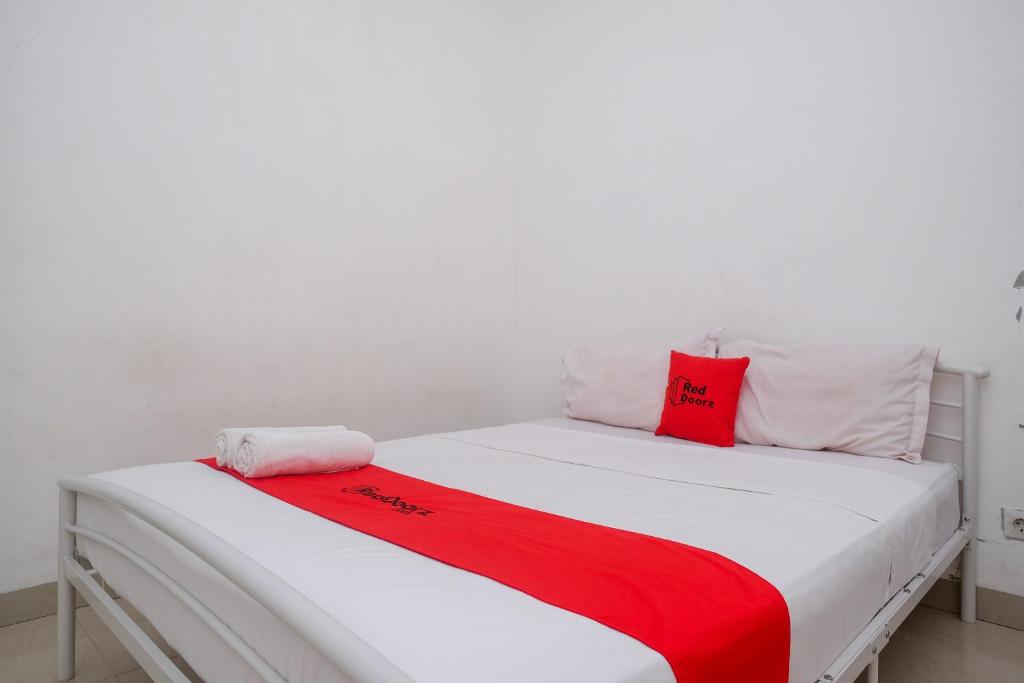 马卡萨RedDoorz at Golden White House Pettarani的一张白色的床,上面有红色枕头