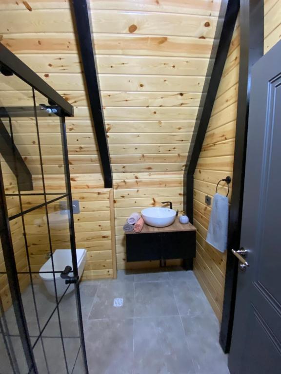 特拉布宗Gohali Bungalov的浴室设有木墙、浴缸和水槽