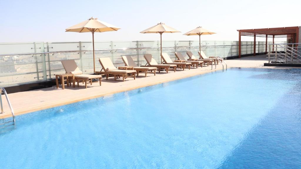 阿布扎比Al Riyadh Hotel Apartments的一座大楼内的游泳池,配有椅子和遮阳伞