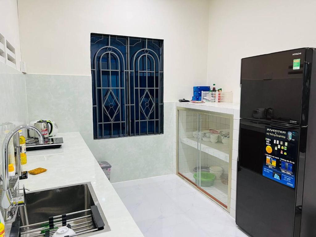 Tây NinhCharis Home- Tay Ninh的厨房配有水槽和黑冰箱。