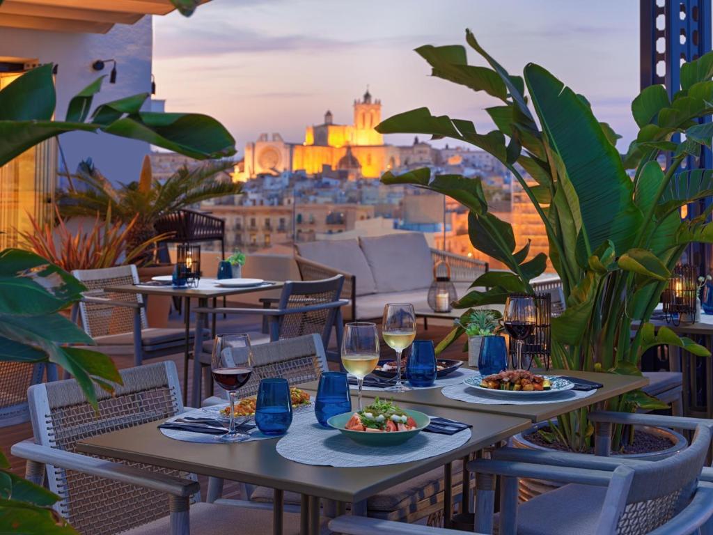 塔拉戈纳H10 Imperial Tarraco 4* Sup的观景阳台的餐桌,配有食物和葡萄酒