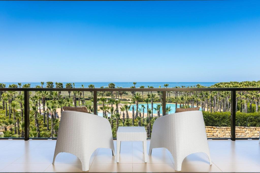 阿尔布费拉NAU Salgados Dunas Suites的阳台上配有两把椅子和一张桌子,享有海景