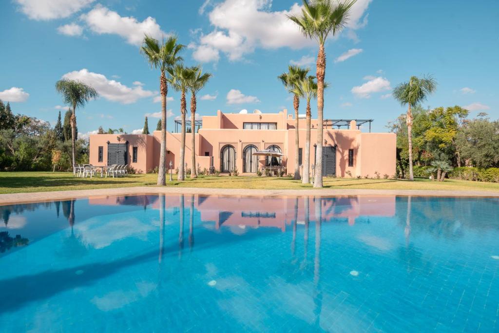 马拉喀什Janat Al Atlas Resort & Spa的游泳池前棕榈树的房子