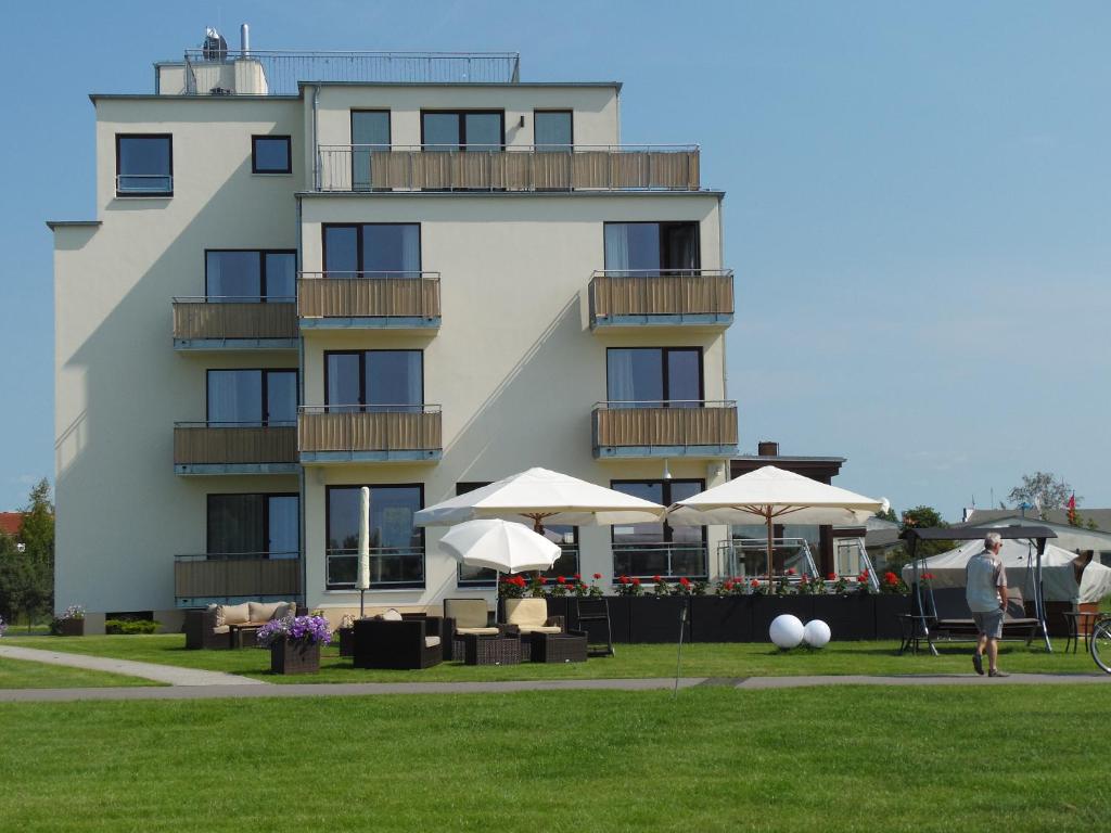 罗斯托克幻娜酒店的前面有桌子和伞的建筑