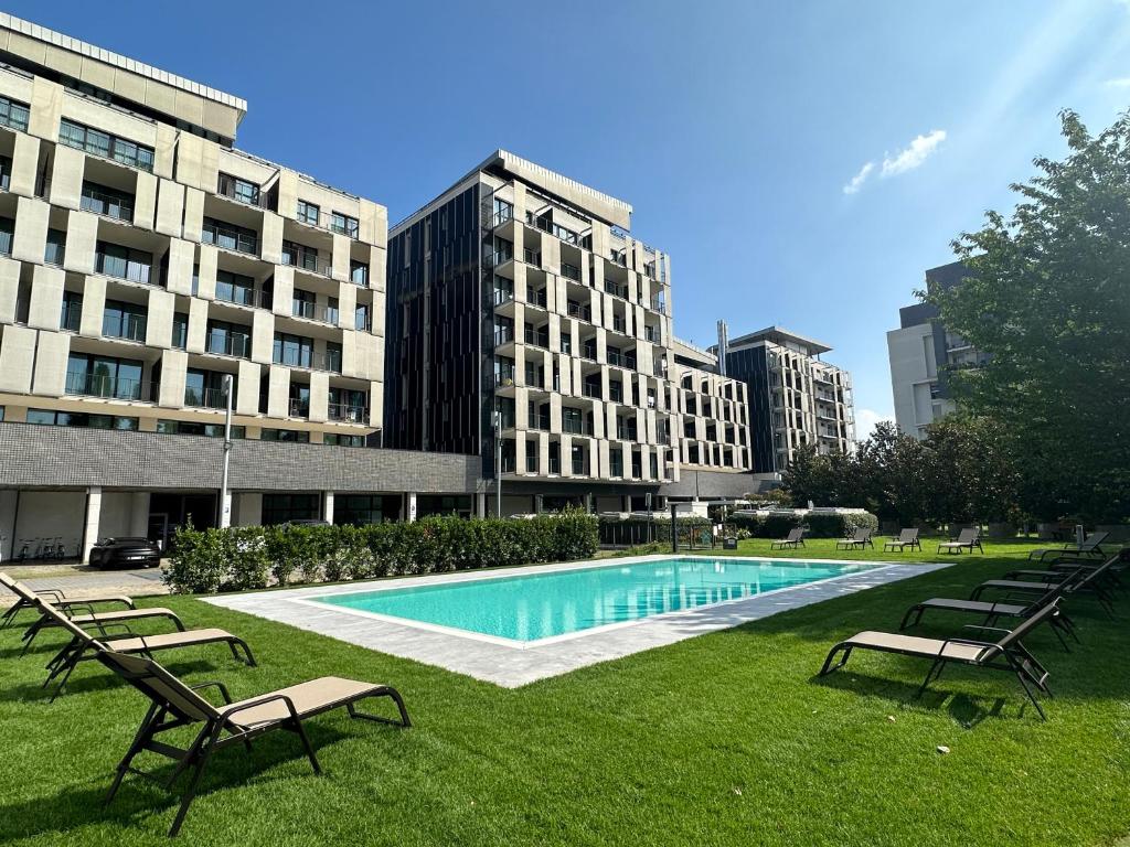 米兰米兰华美达广场酒店的公园内的游泳池,公园内有长椅和建筑物