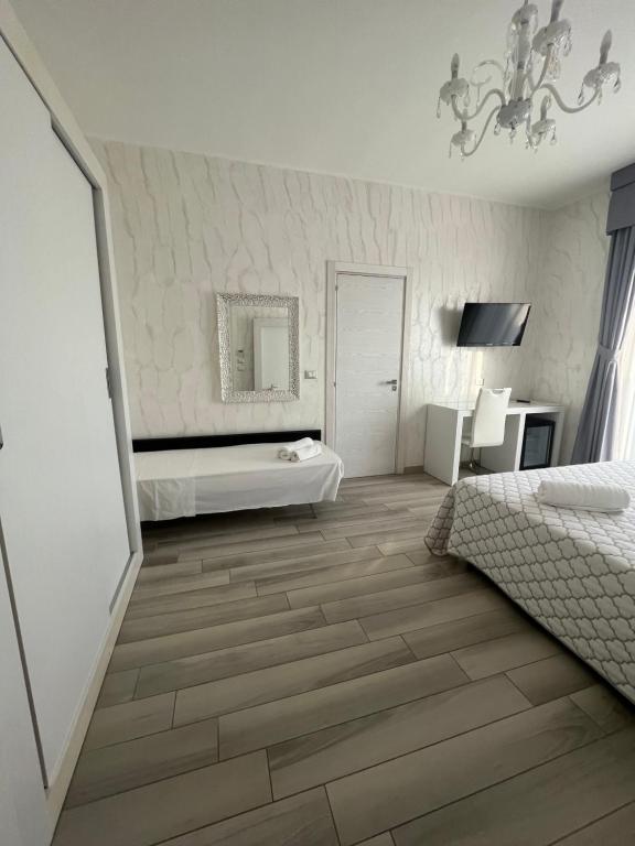 切萨雷奥港Hotel Paladini的卧室设有白色墙壁、木地板和镜子