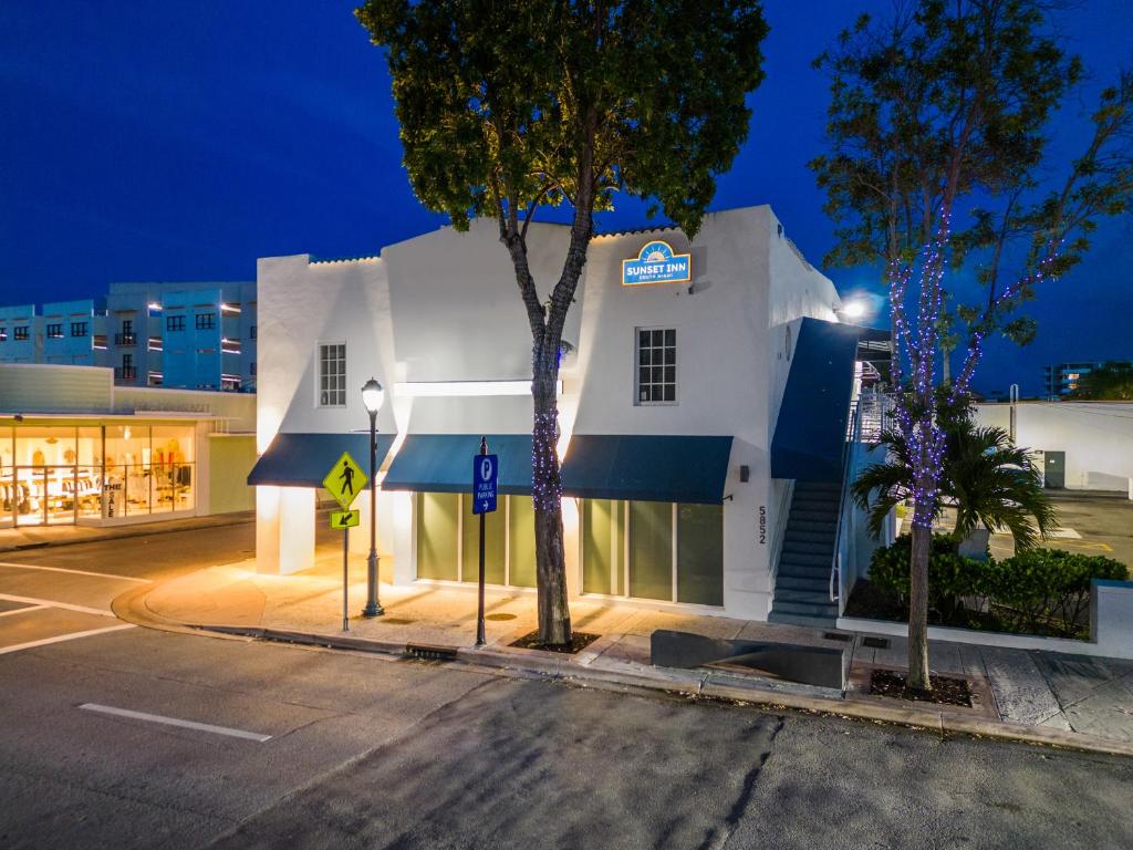 南迈阿密Sunset Inn-South Miami的白色的建筑,在街上有蓝色的遮阳篷