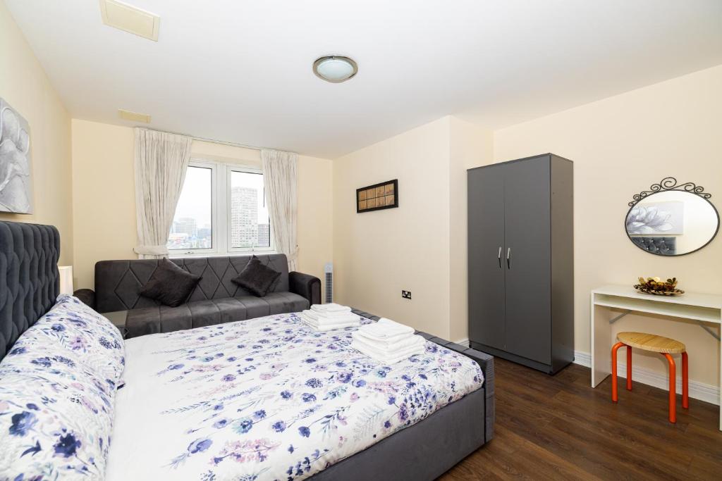 伦敦Two bed Apartment near Canary Wharf的一间卧室配有一张床、一张沙发和一张书桌