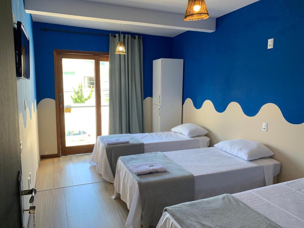 马卡埃Pousada Lazúli的一间设有三张床和蓝色墙壁的房间