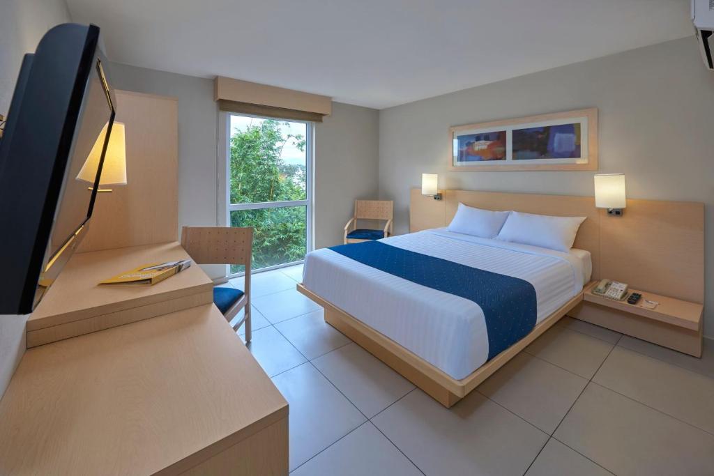 贾拉普夏拉帕城市快捷酒店的一间卧室配有一张床和一张书桌及电视