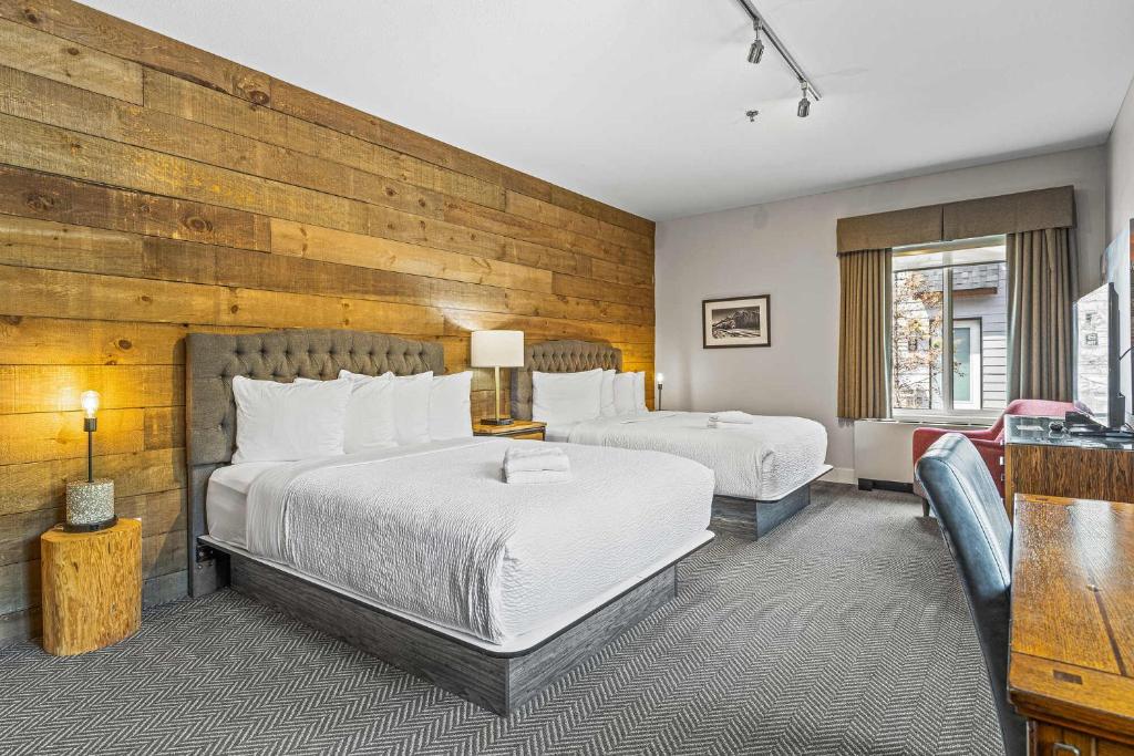坎莫尔Basecamp Lodge Canmore的一间卧室设有两张床和木墙