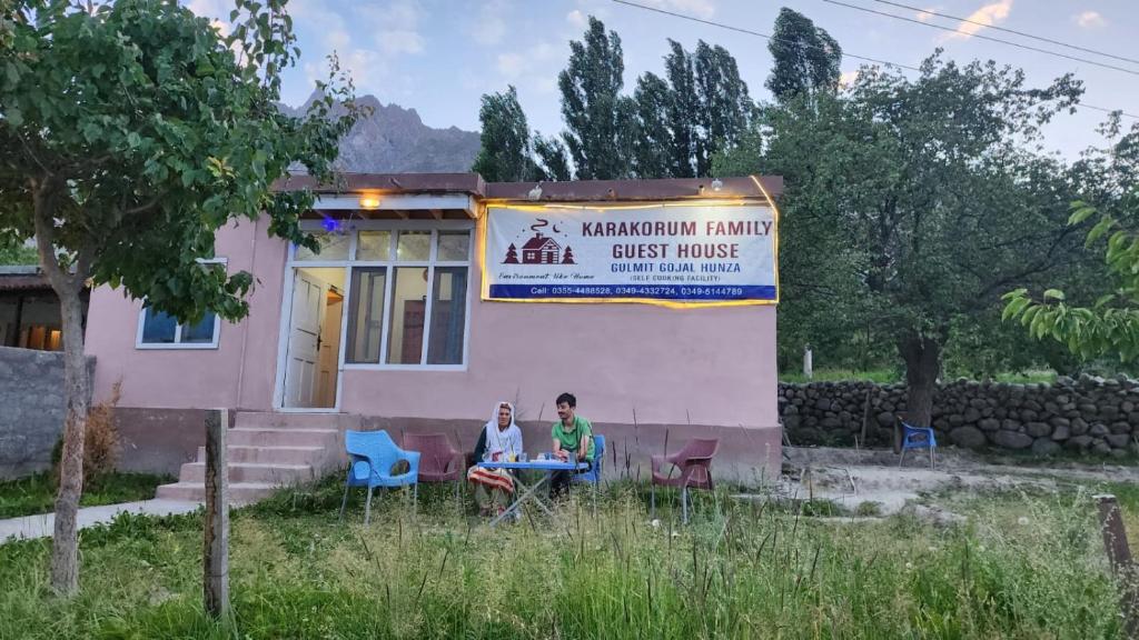 罕萨Karakorum Family Guest House Hunza的两个人坐在房子前面的桌子上