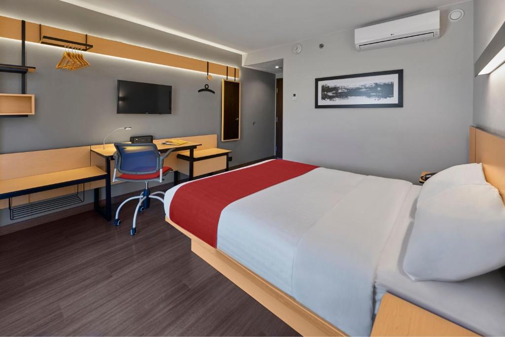 特皮克City Express by Marriott Tepic的酒店客房配有一张床、一张书桌和一台电脑