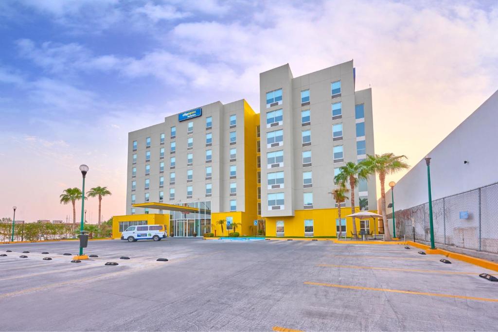墨西卡利墨西卡利都市快捷酒店的酒店停车场,有黄色和白色的建筑