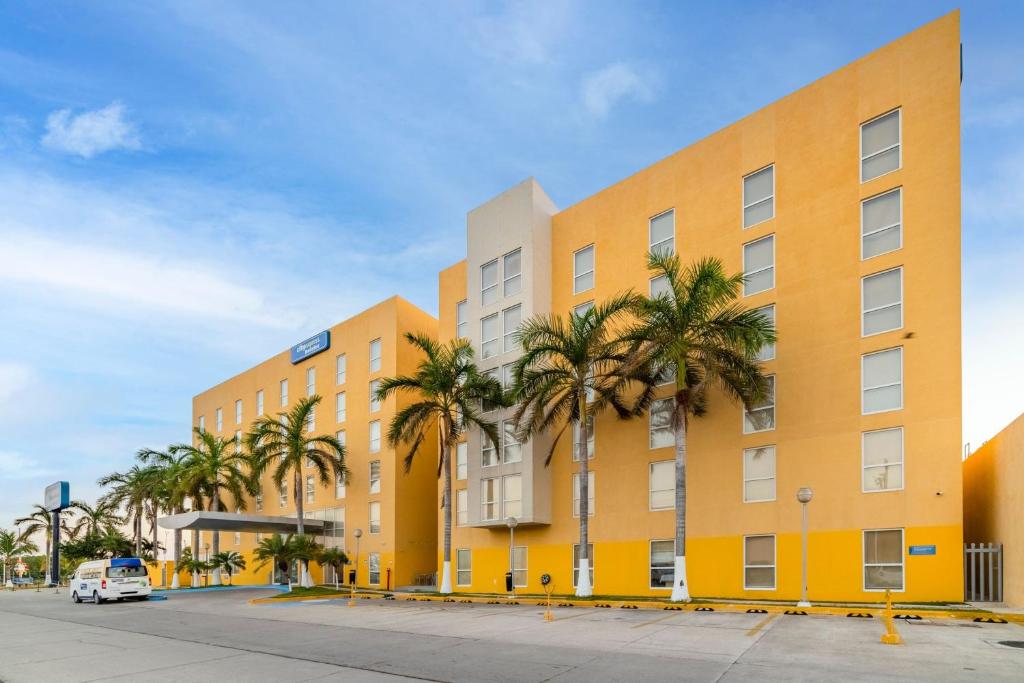 卡门城卡门城市快捷酒店的一座棕榈树的黄色建筑