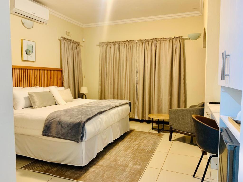 哈博罗内Mmaset Houses bed and breakfast的酒店客房设有一张大床和一张书桌。