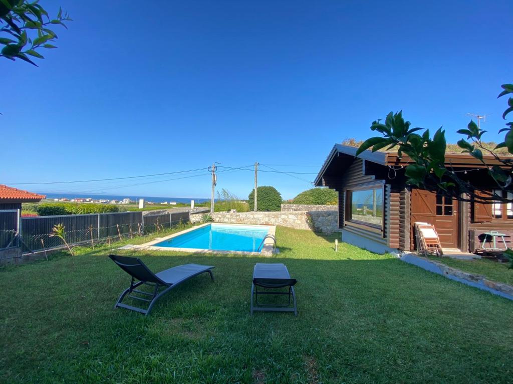 维亚纳堡Encantadora moradia T1, com piscina e vista mar a 500m da praia的一个带两把椅子的庭院和一个游泳池