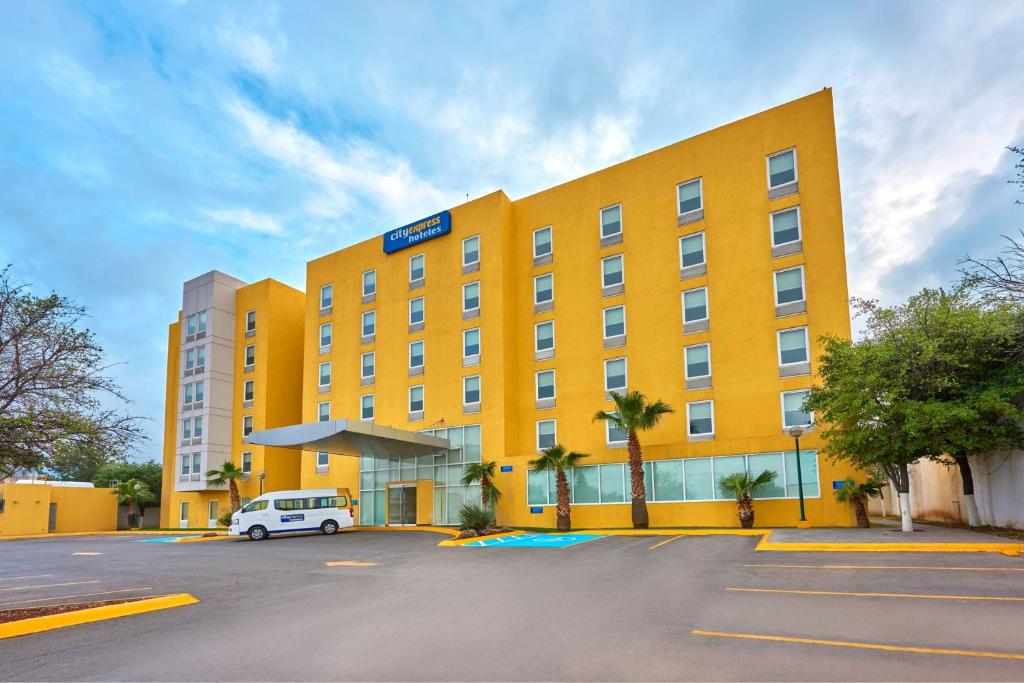 萨尔蒂约萨尔蒂约苏尔城市快捷酒店的一辆黄色的酒店,一辆白色的货车停在停车场