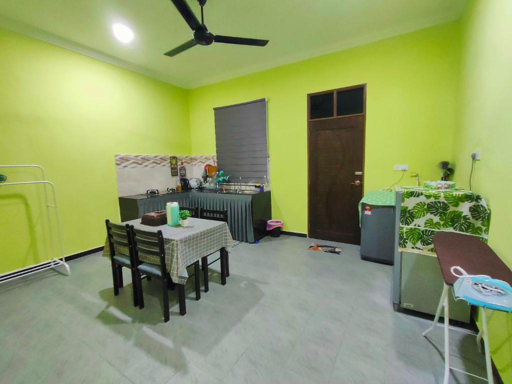 哥打巴鲁Raihan Homestay Kubang Kerian, Free Wifi的一间设有绿色墙壁和桌椅的房间