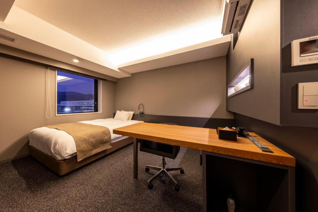敦贺市Hotel Granbinario Tsuruga的一间卧室配有一张床、一张桌子、一张床和一个窗户。