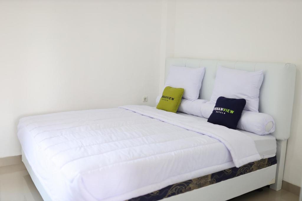 MarosUrbanview Hotel Eropa Maros Near Sultan Hasanuddin Airport的一张带三个枕头的白色床