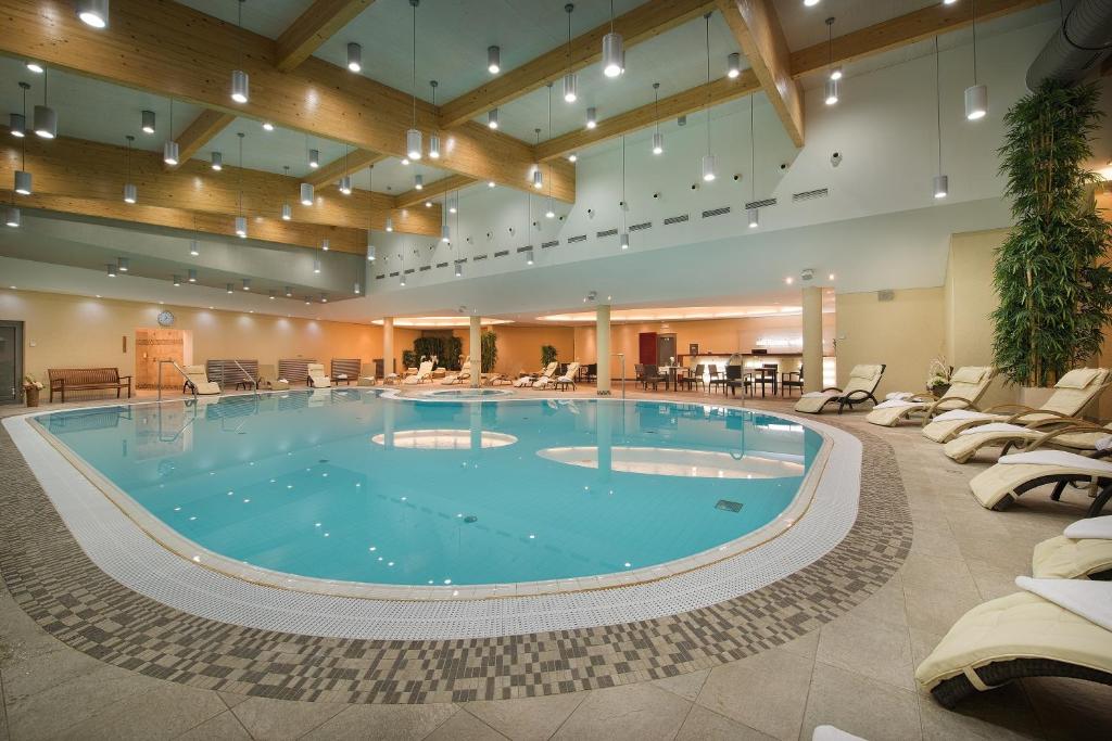 伏尔塔瓦河畔赫卢博卡迪亚曼特疗养酒店的酒店大堂的大型游泳池,配有椅子