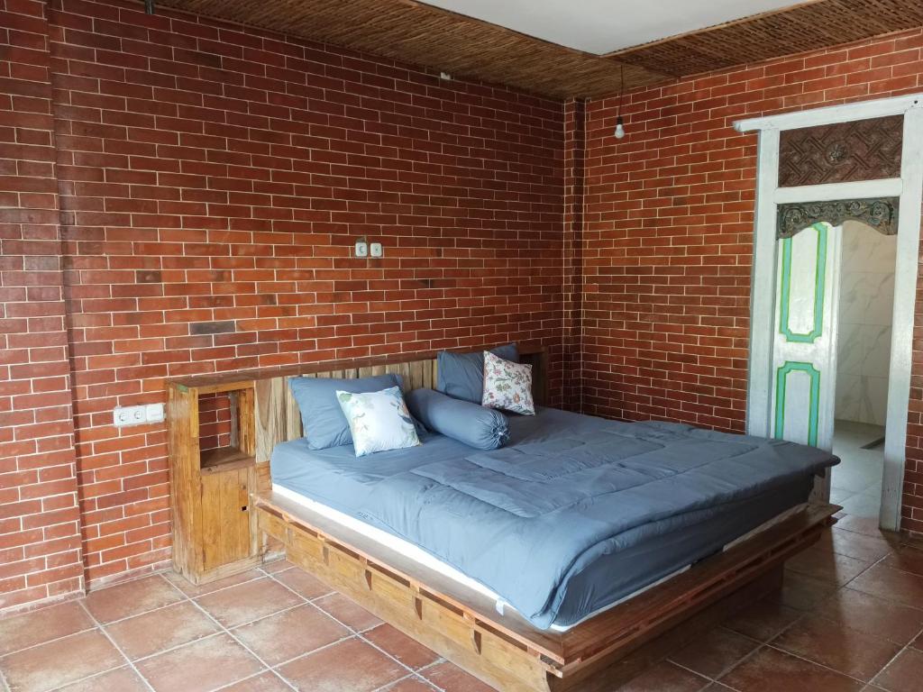 外南梦Pondok isoke bunggalow的砖墙客房的一张床位