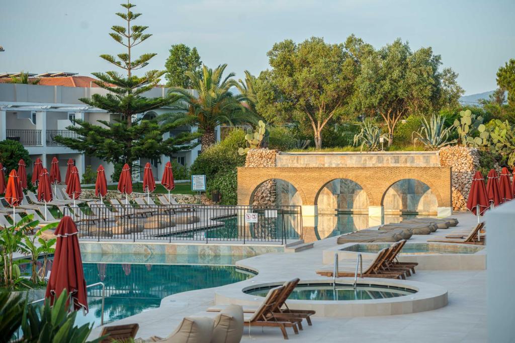 卡拉马孔Bitzaro Grande Hotel & Suites的一个带椅子和红色遮阳伞的游泳池