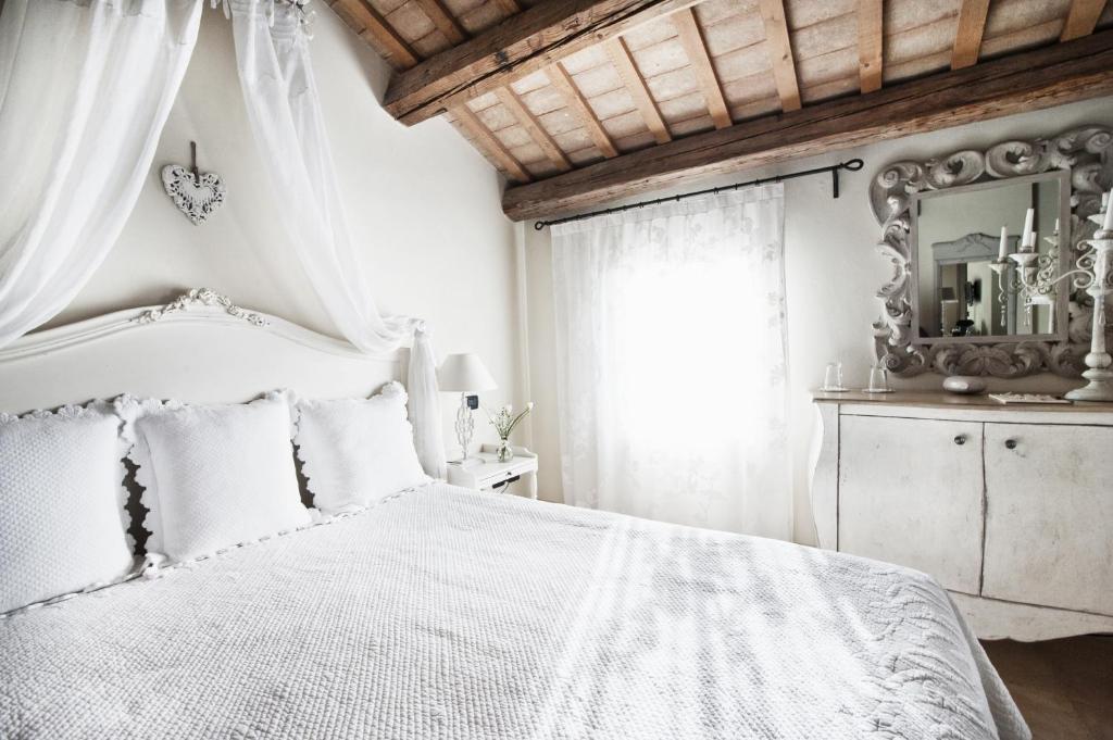 切塞纳蒂科Casina Le Conserve的白色的卧室配有白色的床和镜子