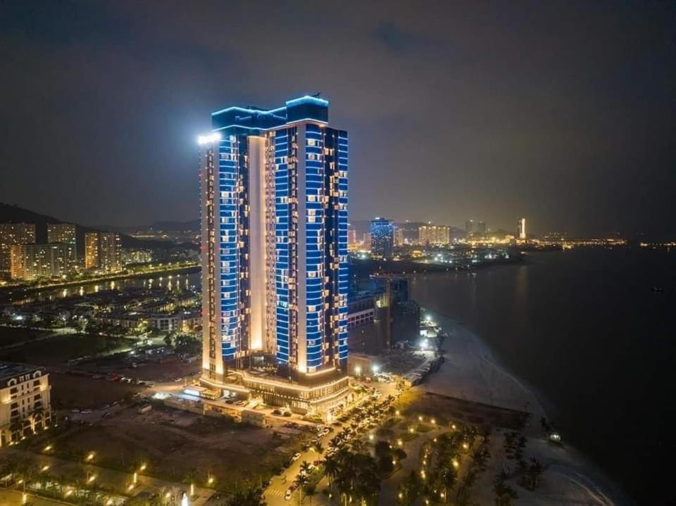 下龙湾Luxury 5 Star A La Carte Residence Ha Long的一座高大的建筑,上面有灯,晚上