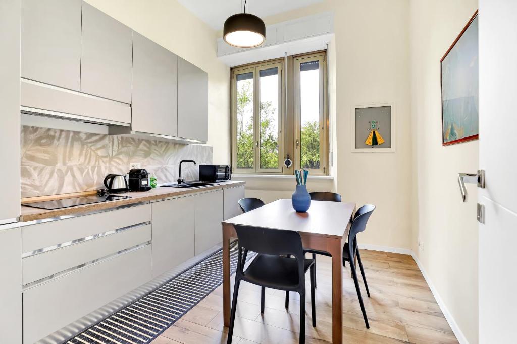 米兰Appartamento Napoli 25 - Affitti Brevi Italia的厨房配有白色橱柜和桌椅
