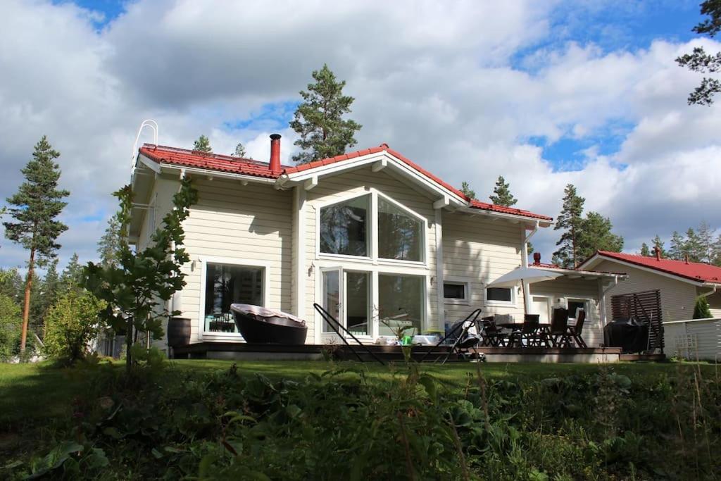 黑诺拉Omakotitalo Vierumäellä X A house near Vierumäki sports center的一间白色的小房子,设有大窗户