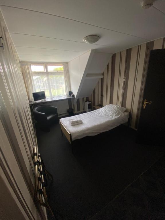 AaldenHet Wapen van Aelden的小房间设有一张床和一把椅子