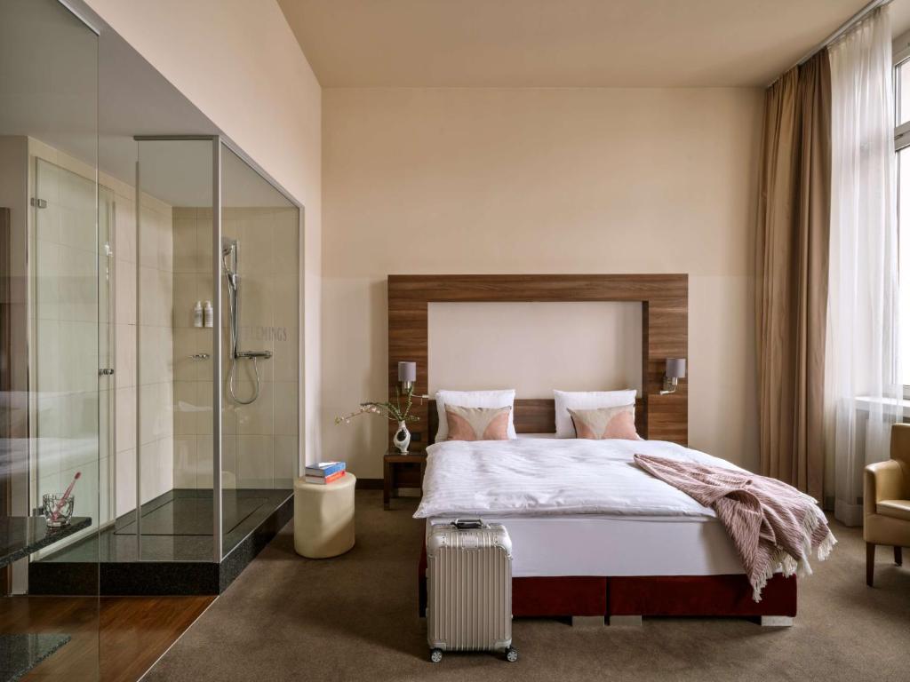 维也纳Flemings Selection Hotel Wien-City的一间卧室设有一张床和一个玻璃淋浴间