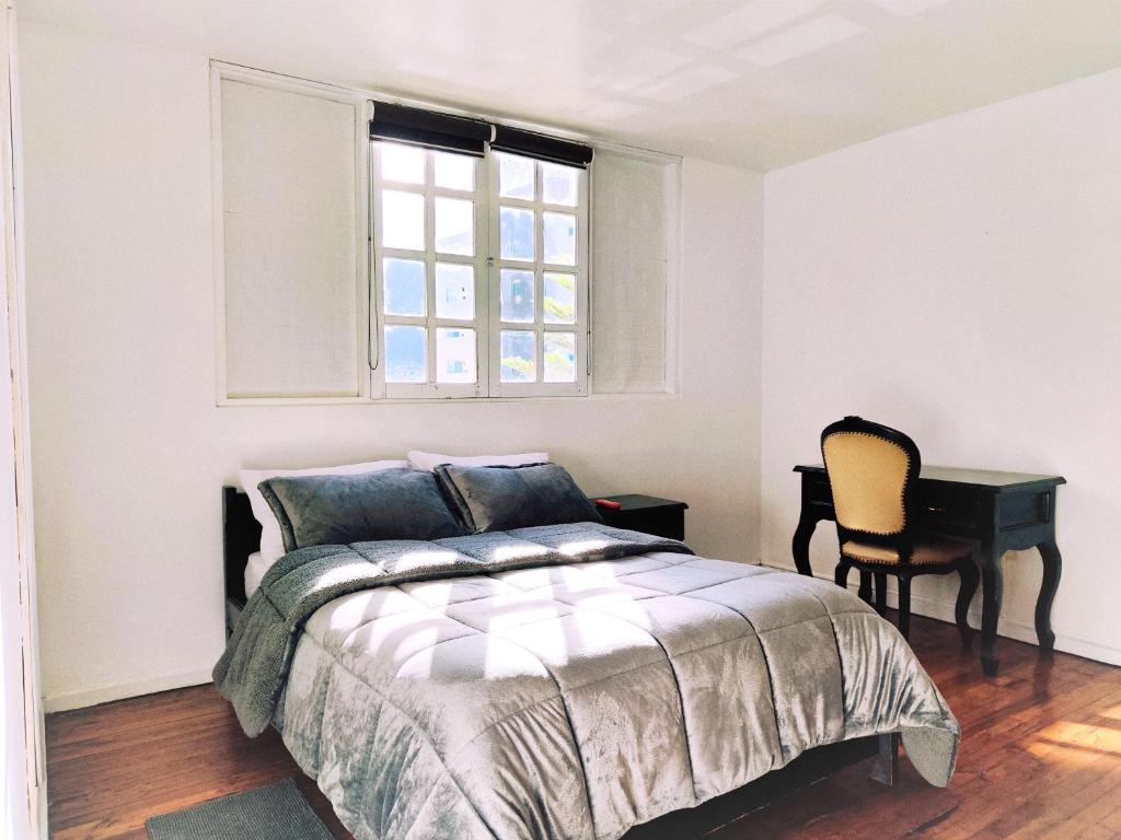 基多Hotel Muros Quito的一间卧室配有一张床、一个窗口和一张书桌