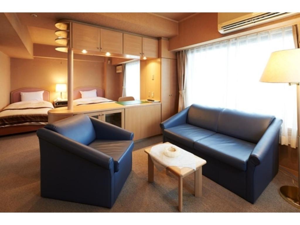 秋田Hotel Alpha Inn Akita - Vacation STAY 67288v的客厅配有两把椅子和一张床