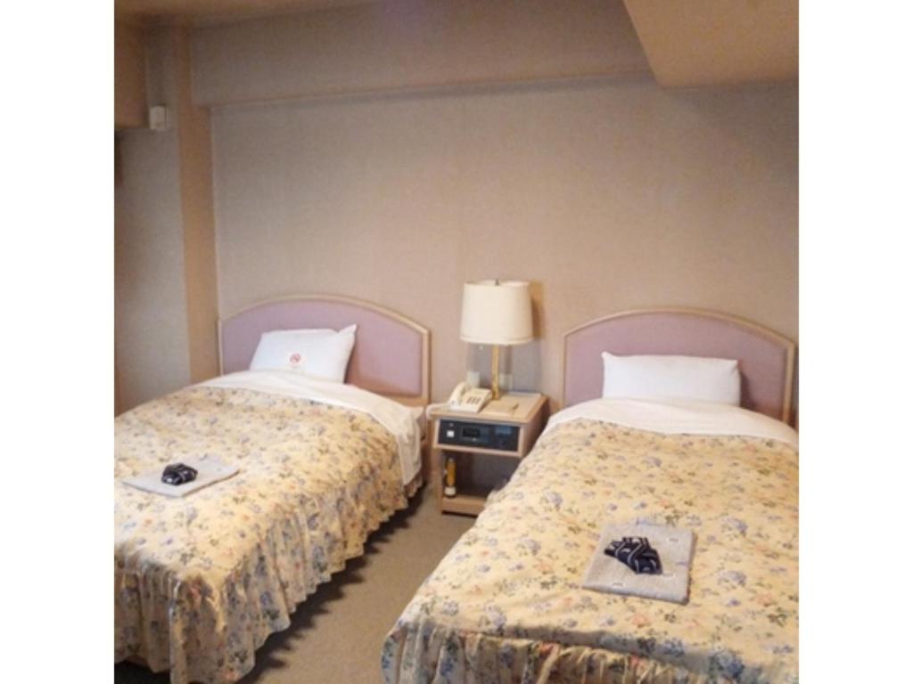 秋田Hotel Alpha Inn Akita - Vacation STAY 67285v的一间卧室配有两张床和一个带灯的床头柜