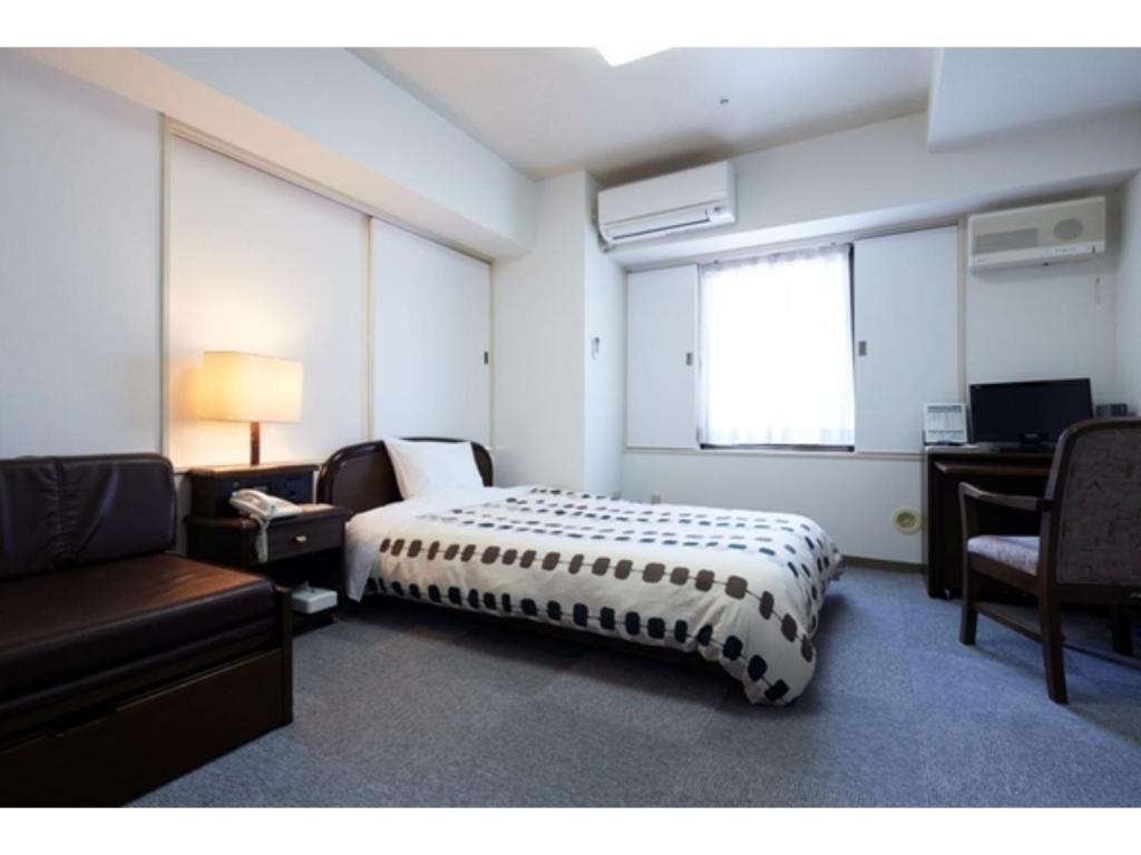 秋田Hotel Alpha Inn Akita - Vacation STAY 67280v的一间卧室配有一张床、一张沙发和一张书桌