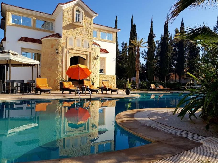 阿加迪尔Villa piscine Agadir的房屋和一个带遮阳伞的游泳池