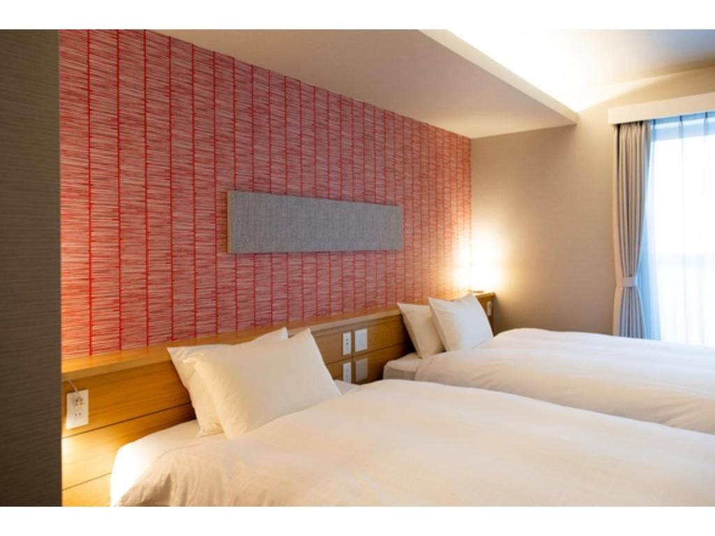 静冈Hotel Celeste Shizuoka Takajo - Vacation STAY 94099v的酒店客房,设有两张床和一面红色瓷砖墙