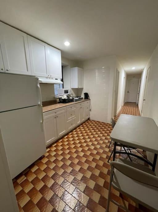纽约1D CLOSe的厨房配有白色橱柜和棕色瓷砖地板。