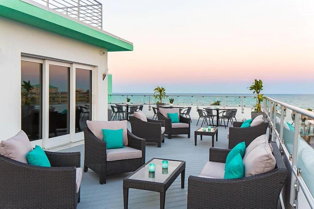 代托纳海滩The Streamline Hotel - Daytona Beach的海滩上带桌椅的甲板