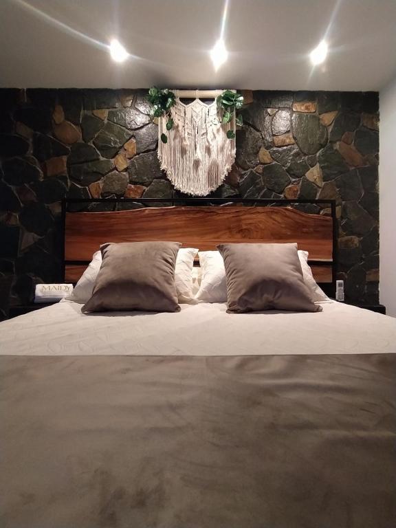 麦德林Maidy Luxury的一间卧室设有一张带石墙的大床